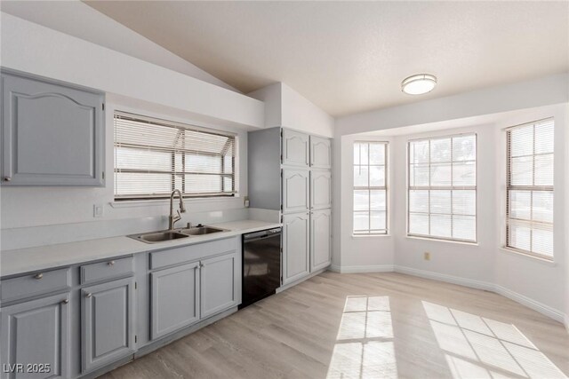 kitchen featuring vaulted ceiling, gray cabinets, black dishwasher, and sink