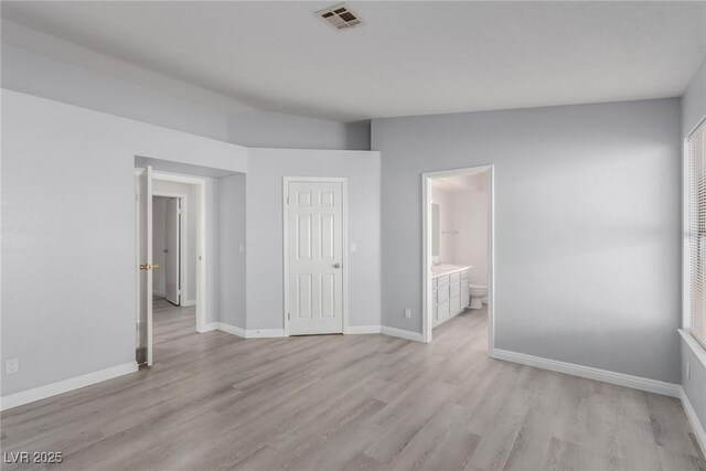 unfurnished bedroom featuring ensuite bath and light hardwood / wood-style floors