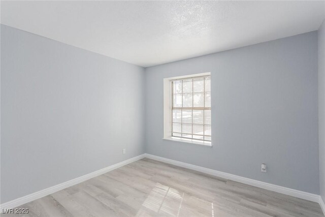 unfurnished room featuring light hardwood / wood-style flooring and a textured ceiling