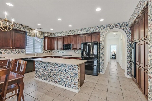 kitchen with light tile patterned flooring, a center island, sink, and black appliances