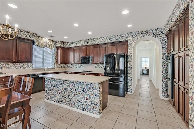 kitchen with a wealth of natural light, a kitchen island, light tile patterned floors, and black appliances