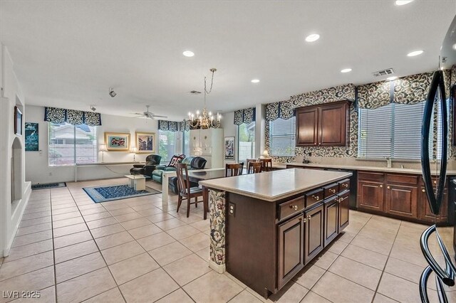 kitchen with dark brown cabinetry, hanging light fixtures, light tile patterned flooring, and a kitchen island