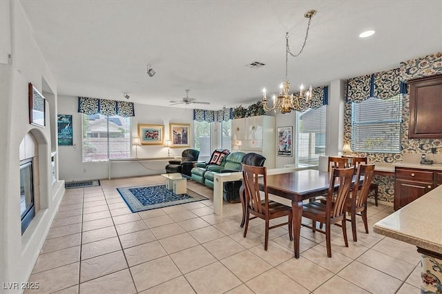 tiled dining area with ceiling fan with notable chandelier