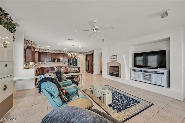 tiled living room with ceiling fan with notable chandelier