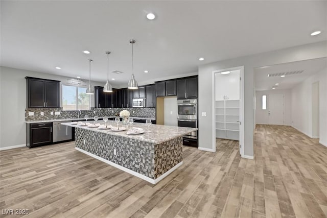 kitchen with tasteful backsplash, light stone countertops, stainless steel appliances, and a kitchen island