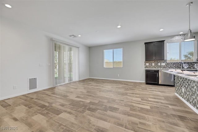 kitchen with light hardwood / wood-style flooring, decorative backsplash, a wealth of natural light, and dishwasher