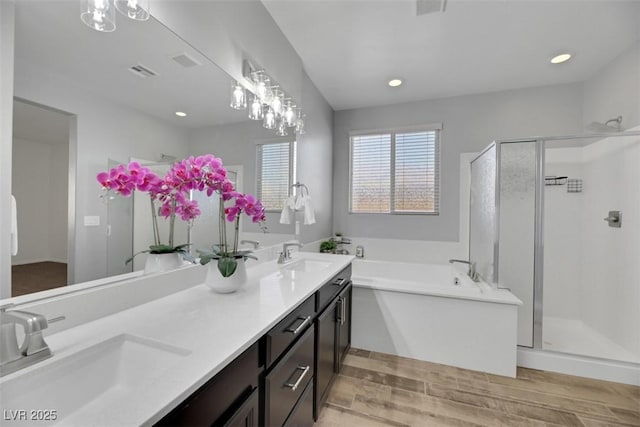 bathroom with hardwood / wood-style flooring, plus walk in shower, and vanity