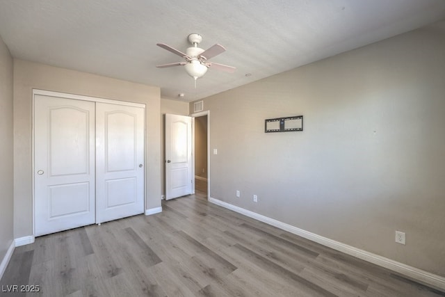 unfurnished bedroom featuring ceiling fan, light hardwood / wood-style floors, and a closet