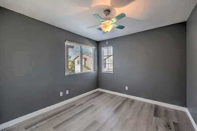 spare room with ceiling fan, a textured ceiling, and light wood-type flooring