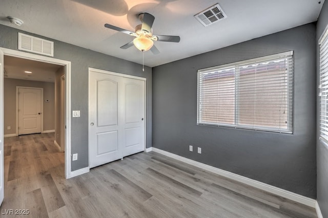 unfurnished bedroom featuring light wood-type flooring, ceiling fan, and a closet