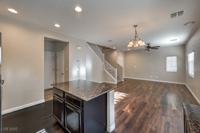 kitchen featuring hanging light fixtures, a kitchen island, dark hardwood / wood-style floors, and dark stone countertops