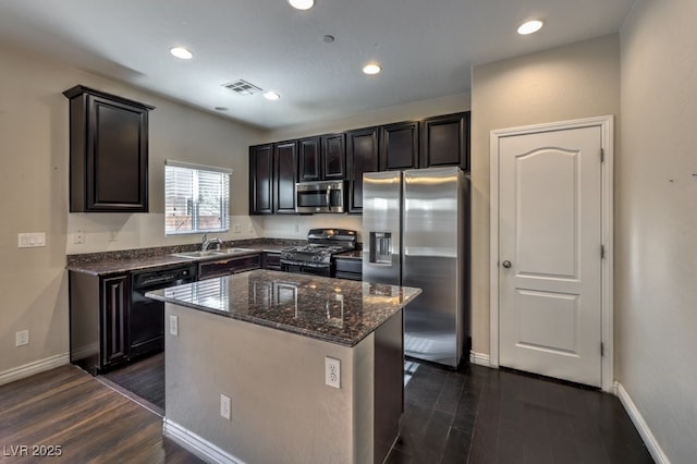 kitchen featuring sink, dark stone countertops, dark hardwood / wood-style floors, black appliances, and a kitchen island