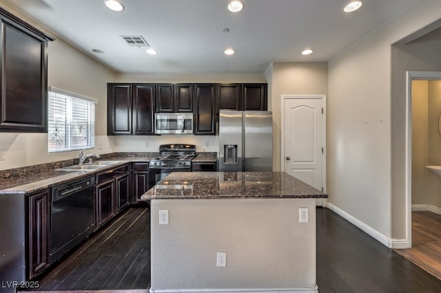 kitchen featuring sink, dark stone countertops, dark hardwood / wood-style flooring, a kitchen island, and black appliances