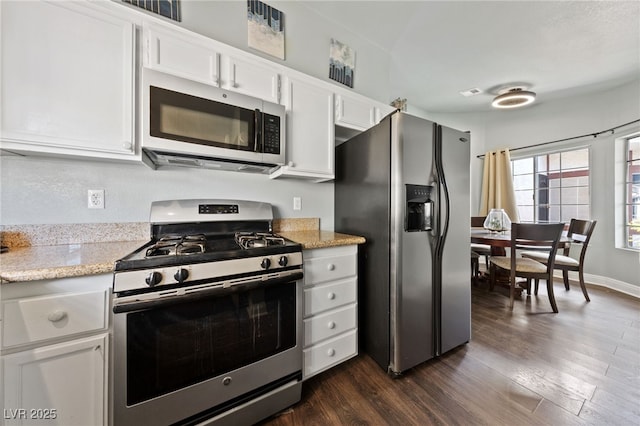 kitchen with white cabinetry, appliances with stainless steel finishes, dark hardwood / wood-style flooring, and light stone countertops