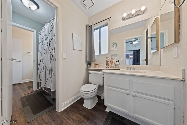 bathroom with hardwood / wood-style flooring, ceiling fan, vanity, a shower with curtain, and toilet