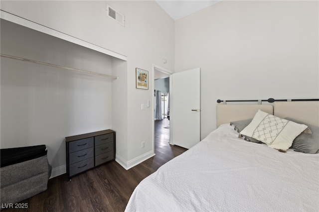 bedroom with dark wood-type flooring, high vaulted ceiling, and a closet