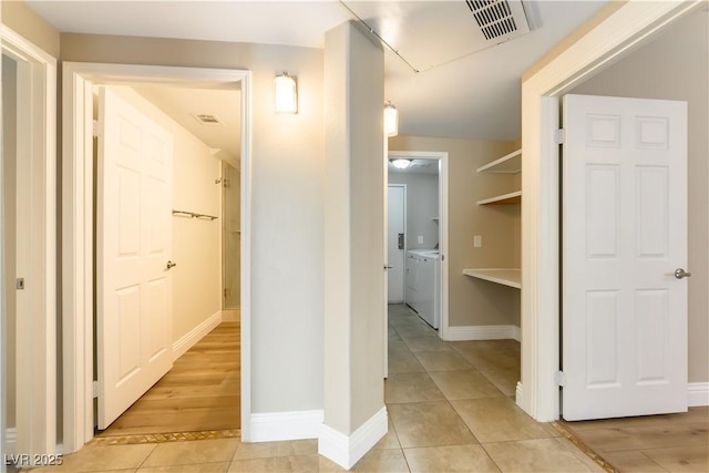 corridor with light tile patterned floors and washer and clothes dryer