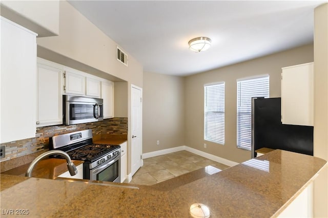 kitchen with light tile patterned flooring, appliances with stainless steel finishes, white cabinetry, sink, and decorative backsplash