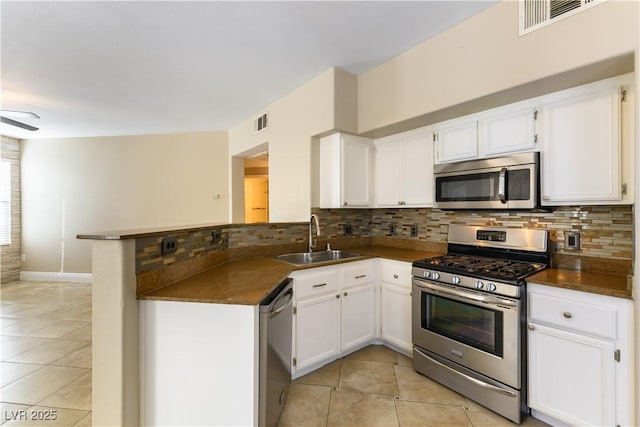 kitchen featuring sink, light tile patterned floors, stainless steel appliances, white cabinets, and kitchen peninsula