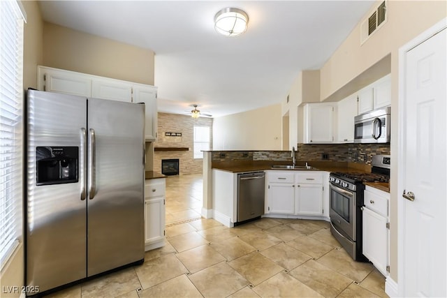 kitchen with stainless steel appliances, sink, decorative backsplash, and white cabinets