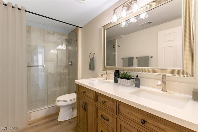 bathroom featuring hardwood / wood-style flooring, vanity, toilet, and a shower with door