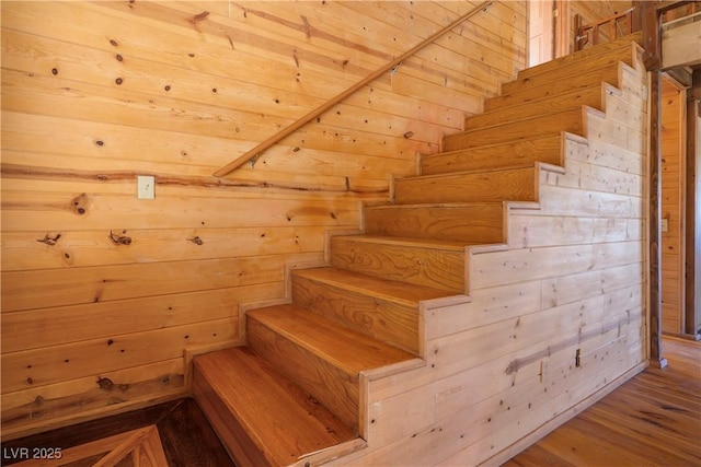 staircase featuring hardwood / wood-style flooring and wooden walls