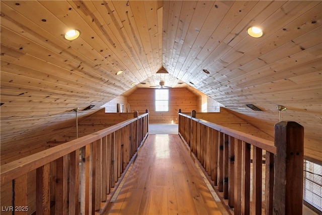 hallway with lofted ceiling, light wood-type flooring, wooden ceiling, and wood walls