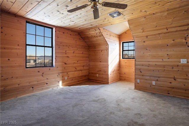 bonus room featuring lofted ceiling, wood walls, wooden ceiling, ceiling fan, and carpet