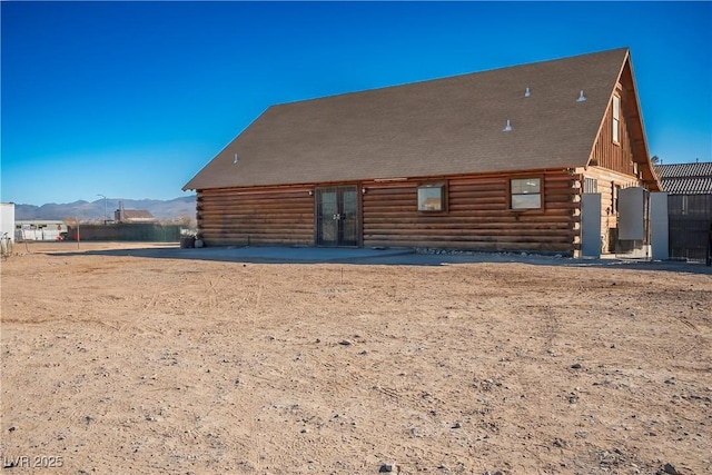 back of property with a mountain view and a patio