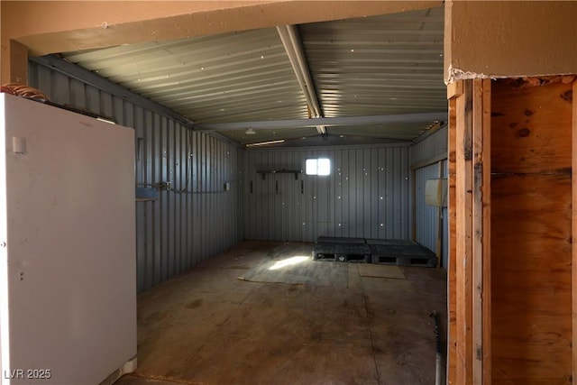 basement featuring wooden walls and white fridge