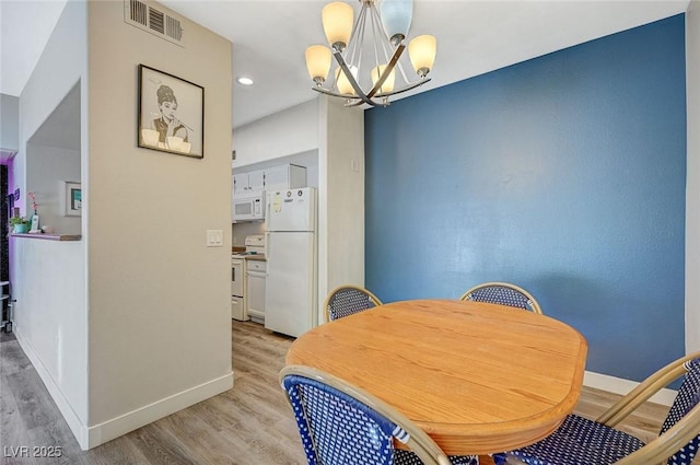 dining room with light hardwood / wood-style floors and a notable chandelier