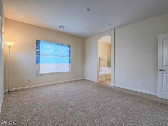 unfurnished bedroom featuring ensuite bath and light colored carpet