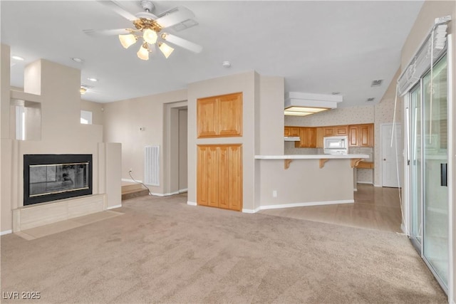 unfurnished living room featuring ceiling fan and light carpet