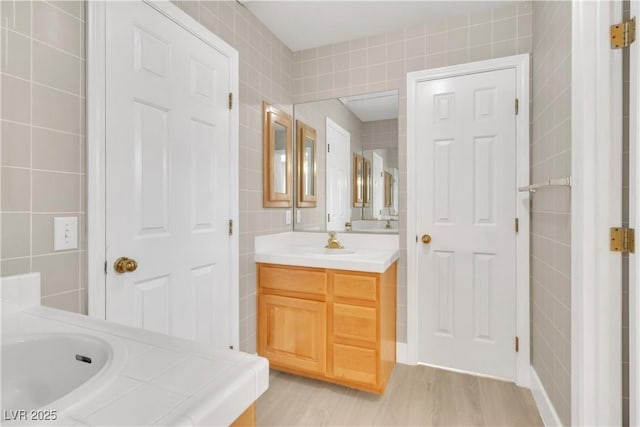 bathroom with hardwood / wood-style flooring, vanity, and tile walls