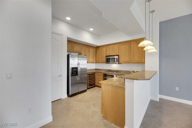 kitchen featuring appliances with stainless steel finishes, light stone counters, kitchen peninsula, decorative light fixtures, and beverage cooler