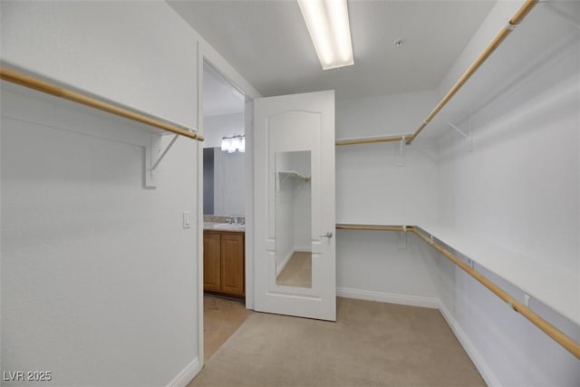 walk in closet with light carpet and sink