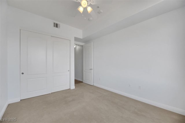 unfurnished bedroom with ceiling fan, light colored carpet, and a closet