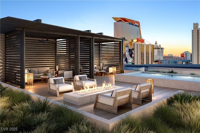 patio terrace at dusk with a pool and an outdoor living space with a fire pit