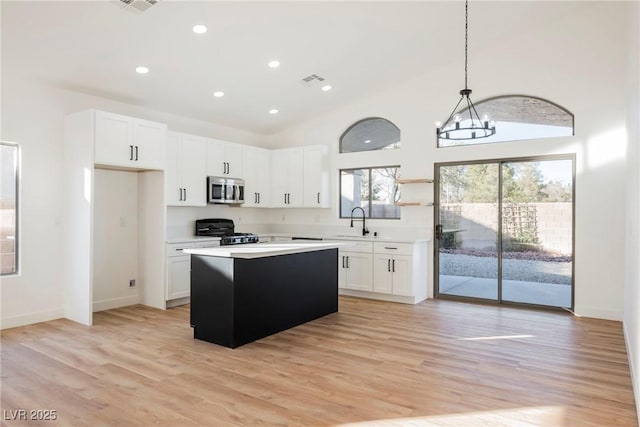 kitchen featuring range, white cabinetry, high vaulted ceiling, a kitchen island, and decorative light fixtures