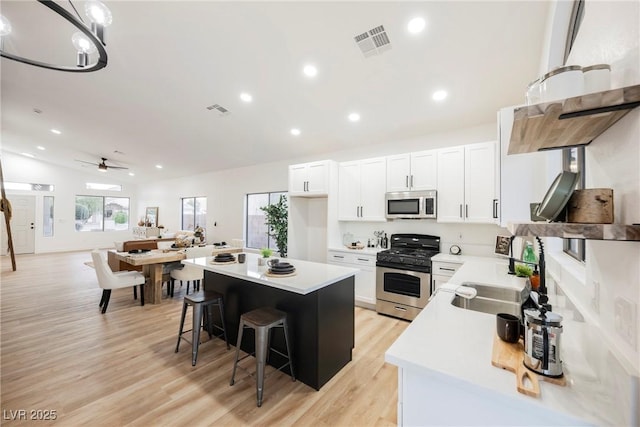 kitchen featuring sink, a breakfast bar, white cabinetry, stainless steel appliances, and a center island