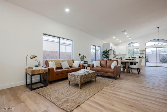 living room with high vaulted ceiling and light hardwood / wood-style floors