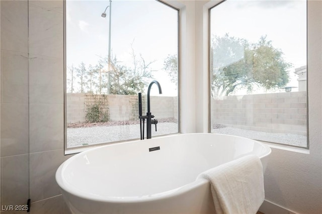 bathroom with a tub to relax in and sink