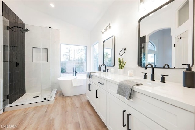 bathroom featuring independent shower and bath, wood-type flooring, lofted ceiling, and vanity