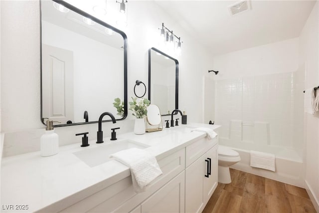 full bathroom featuring hardwood / wood-style flooring, vanity, bathtub / shower combination, and toilet