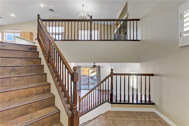 stairs with tile patterned flooring, ceiling fan with notable chandelier, and high vaulted ceiling