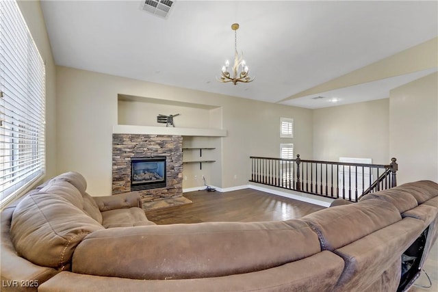 living room featuring hardwood / wood-style floors, built in features, a fireplace, lofted ceiling, and an inviting chandelier