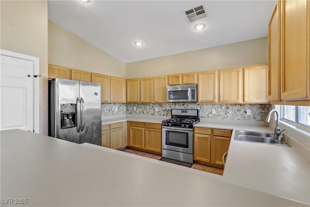 kitchen featuring sink, appliances with stainless steel finishes, backsplash, vaulted ceiling, and light brown cabinets