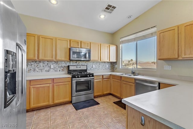 kitchen with appliances with stainless steel finishes, light brown cabinetry, sink, and light tile patterned floors