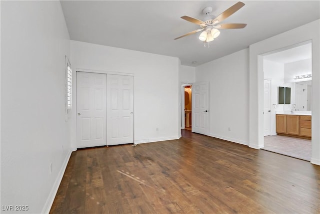 unfurnished bedroom featuring ensuite bathroom, sink, dark hardwood / wood-style flooring, ceiling fan, and a closet