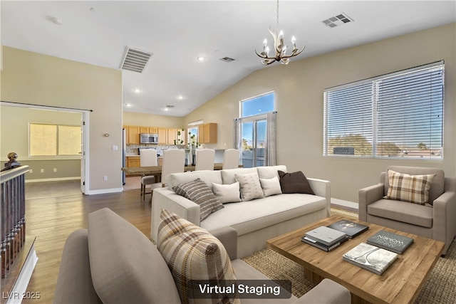 living room featuring lofted ceiling, a chandelier, and light hardwood / wood-style floors